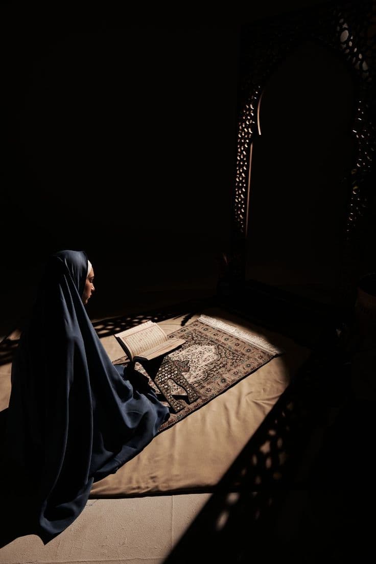 A student at study, prayer rug underfoot.